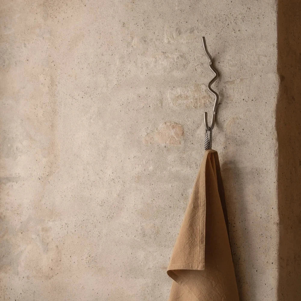Ferm Living Curvature Hook in black metal, wall-mounted accessory for hanging items, modern minimalist design.