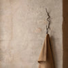 Ferm Living Curvature Hook in black metal, wall-mounted accessory for hanging items, modern minimalist design.
