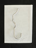 Ferm Living Curvature Hook in black metal, mounted on wall, used for hanging accessories or decor items.