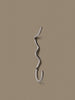 Ferm Living Curvature Hook in black, minimalist metal wall hook for accessories, mounted on a white wall.