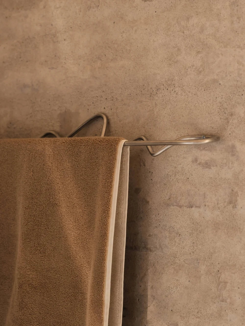 Ferm Living Curvature Towel Hanger in matte black with a sleek, curved design mounted on a bathroom wall for towels.