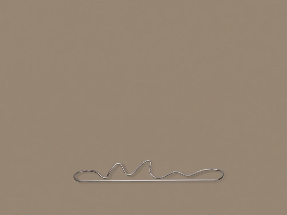 Ferm Living Curvature Towel Hanger in black metal, wall-mounted accessory with curved design for hanging towels or accessories.