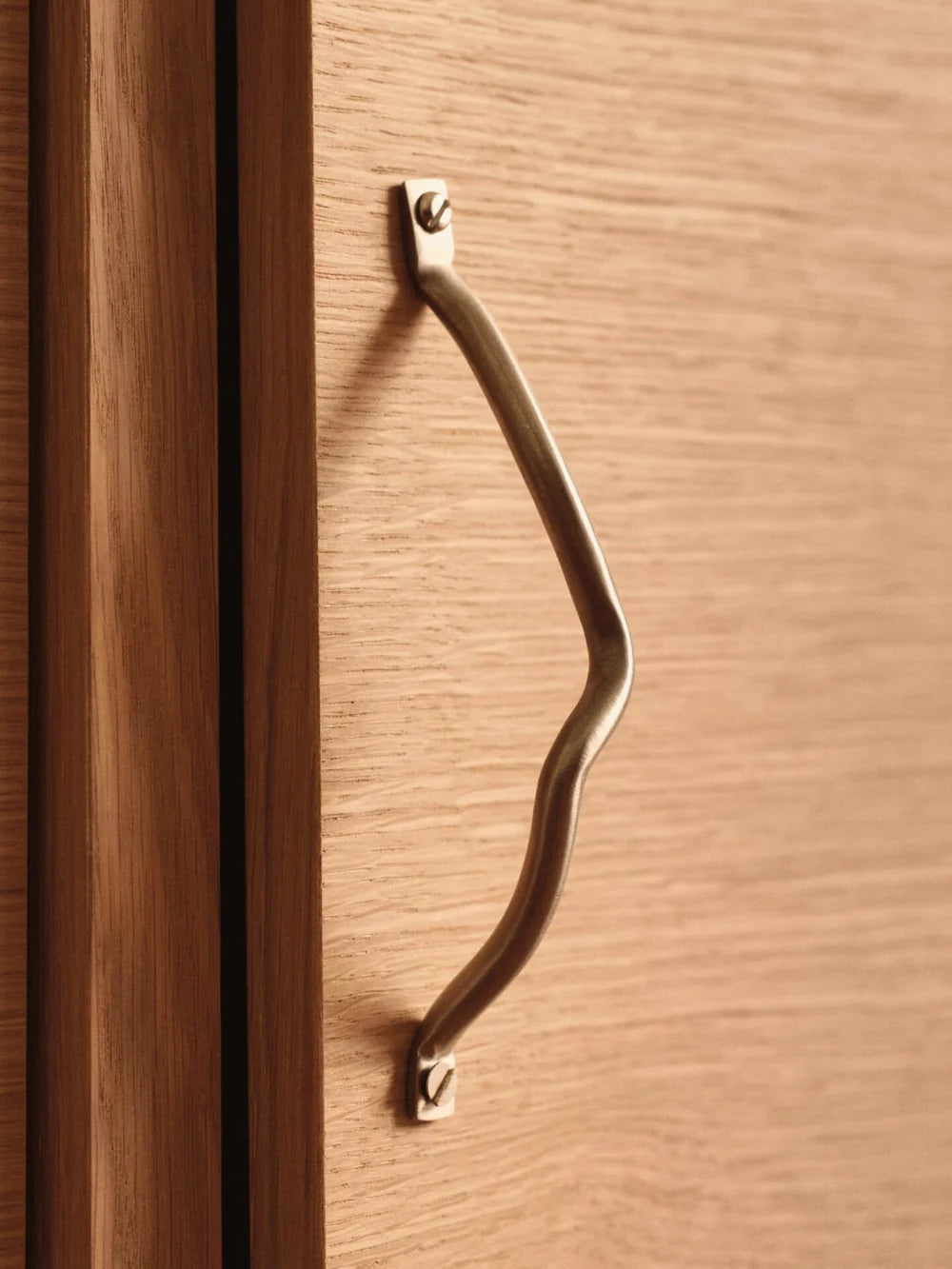 Ferm Living Curvature Handle in natural wood finish, modern accessory for furniture or cabinetry, with smooth curved design