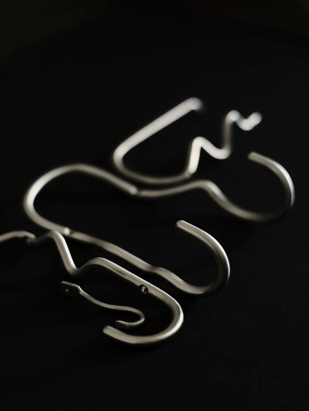 Set of three Ferm Living curvature hooks, modern wall-mounted accessories with sleek, curved design for hanging items.