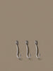 Set of three Ferm Living curvature hooks, modern accessories for hanging items, with sleek, curved design and matte finish.