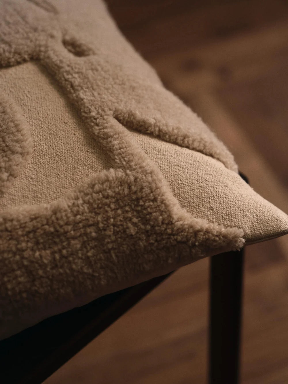 Ferm Living Cilla tufted cushion with textured fabric and decorative buttons, accenting a cozy armchair or sofa.