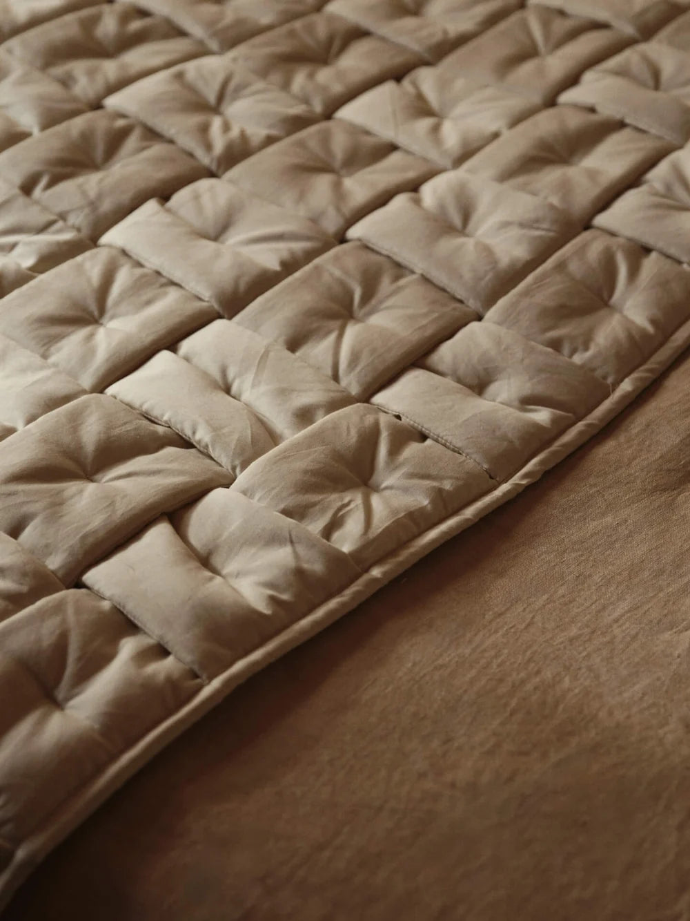 Ferm Living Sofi Bed Runner in neutral fabric draped over a neatly made bedroom bed with pillows and cozy decor.
