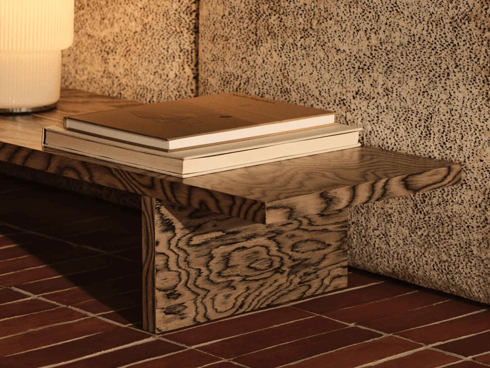 Ferm Living Kona Display Table used as seating, featuring a modern design with a woven seat and wooden frame.