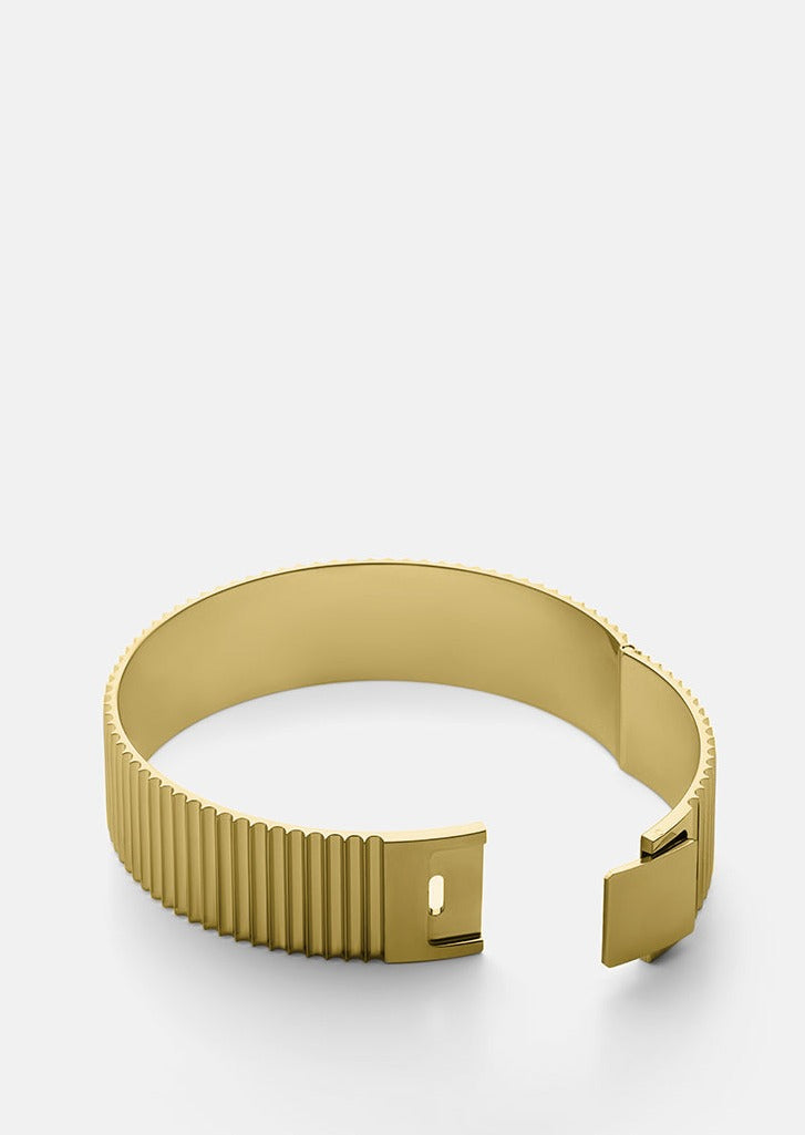 Gold plated ribbed clasp bangle by Skultuna, showcasing a sleek, circular accessory with textured ribbed design.