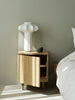 Rib Bedside Table by Normann Copenhagen featuring a wooden oak finish and a sleek, modern design with a table lamp.