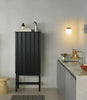 High Rib Cabinet by Normann Copenhagen in soft black with dark brown Hinx lamp, showcasing modern storage design.