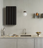 Rib Wall Cabinet by Normann Copenhagen in soft black, mounted on a wall, styled with dark brown Hinx lamp and decorative items.