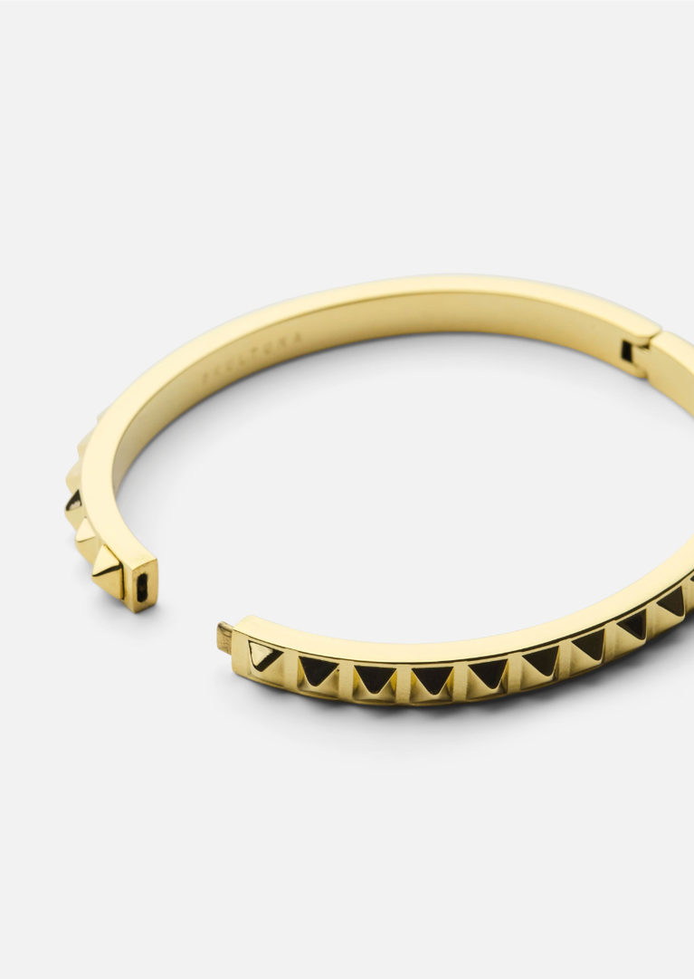Gold plated Rivets Bangle by Skultuna, showing close-up of the sleek, modern jewelry design with rivet details on the gold accessory.