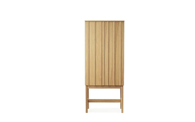 High ribbed oak cabinet by Normann Copenhagen for storage, featuring a modern design with vertical grooves and sleek handles.
