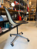 Vintage Charles Eames PSCC Herman Miller rolling task chair with black seat and wooden armrests, modern seating design.