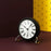 Roman table clock by Arne Jacobsen, minimalist accessories with a sleek design, showcasing a classic timepiece on a smooth surface.