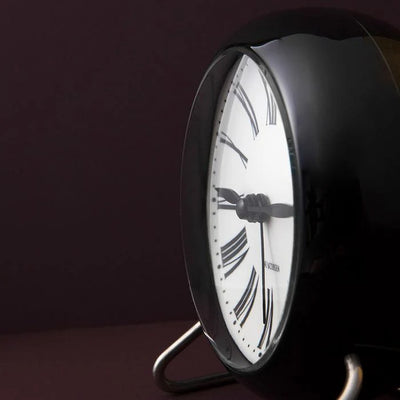 Roman table clock by Arne Jacobsen, minimalist accessory with sleek design, featuring a white dial and silver-tone case.