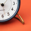 Arne Jacobsen Station Table Clock, a sleek modern accessory with minimalist design and clean lines, displayed on a wooden surface