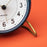 Arne Jacobsen Station Table Clock, a sleek modern accessory with minimalist design and clean lines, displayed on a wooden surface