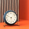Arne Jacobsen Station Table Clock resting on a wooden surface, showcasing a sleek, minimalist design in natural light.