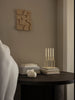 A ivory Audo Copenhagen Kubus candle holder with a minimalist geometric design, used as an elegant home accessory.