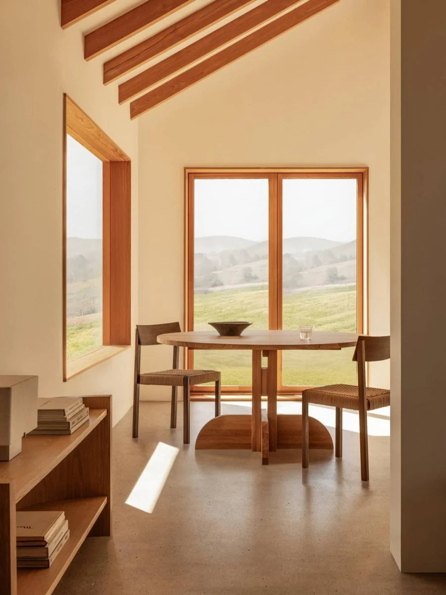 A seating area featuring the Puffin Dining Table by Audo Copenhagen with Mauro dining chairs and crescent shelving in a modern interior.