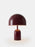 Tom Dixon Bell portable light in high-gloss burgundy, showcasing its sleek, rounded design and compact shape for modern lighting.