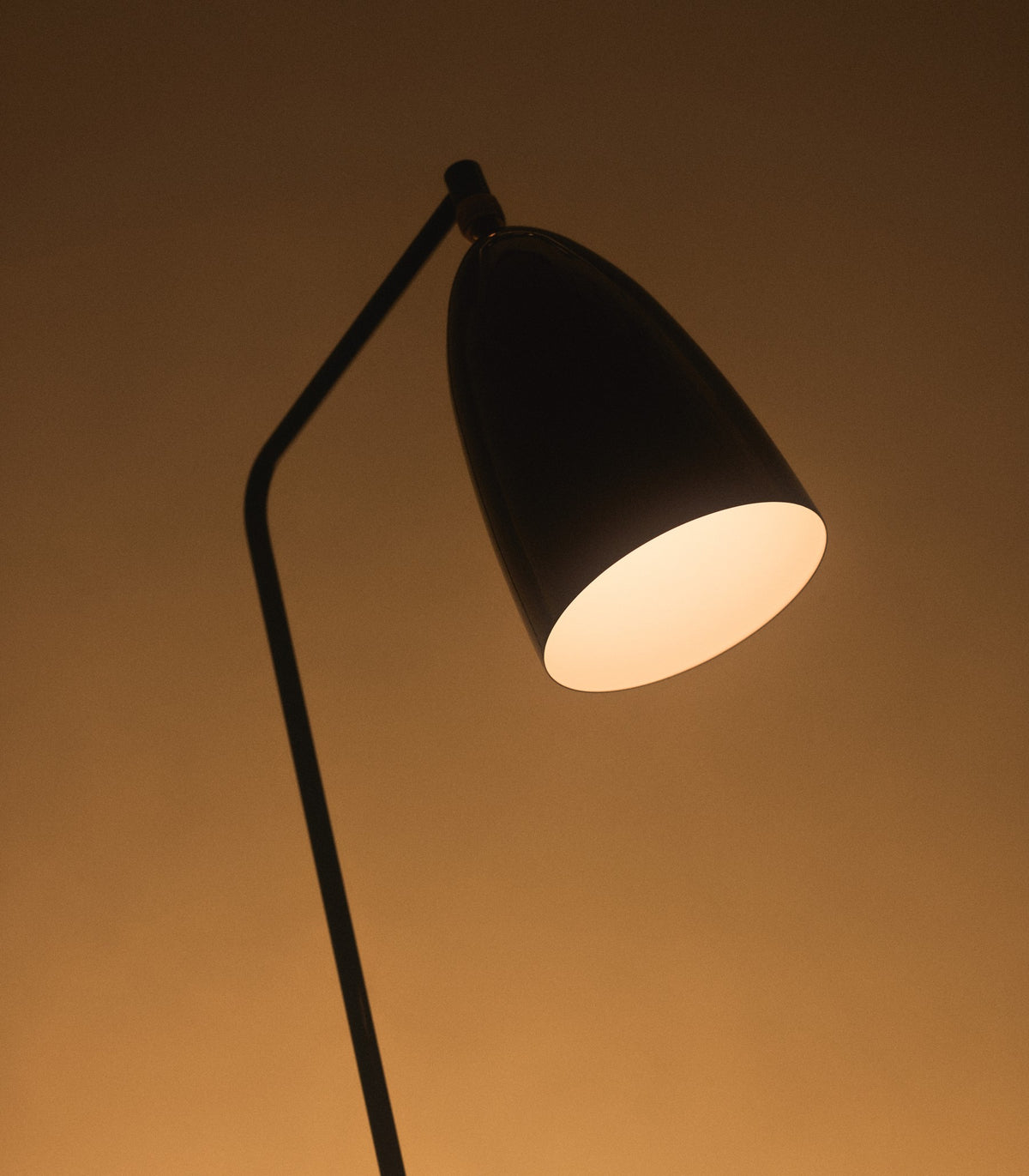 Gubi Gräshoppa floor lamp with adjustable brass and black steel design, modern lighting fixture for living spaces.