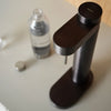Stelton Brus Carbonator accessory for soda maker, sleek black plastic with ergonomic handle and carbonating mechanism.