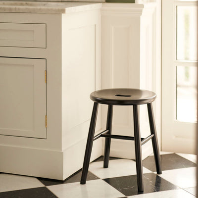 Black J27 stool by FDB Møbler with wooden legs, showcasing a sleek, minimalist seating design.