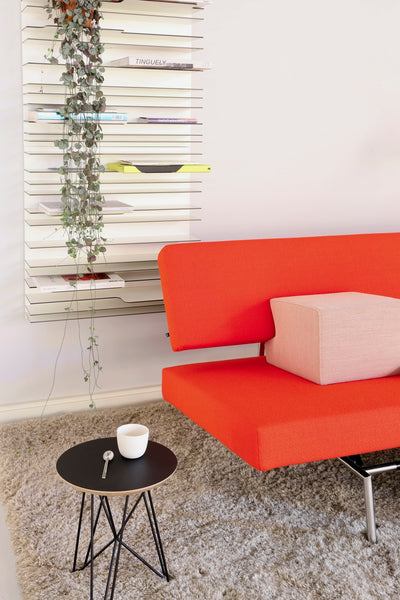 Orange upholstered IJhorst side table by Pastoe with sleek wooden legs, showcasing modern design and smooth surface detail.