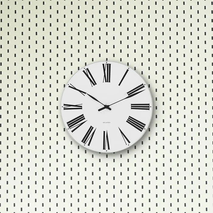 Roman wall clock by Arne Jacobsen showing a minimalist design with Roman numerals on a sleek wall.