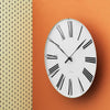 Roman wall clock by Arne Jacobsen, minimalist accessories with a sleek design and Roman numeral dial mounted on a wall.
