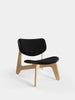 Slab lounge chair by Tom Dixon with natural brushed oak frame and black leather seating, modern seating furniture.