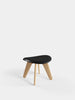 Tom Dixon Slab Ottoman with a natural brushed oak base and black leather top, used as stylish seating.