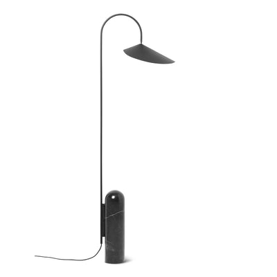Ferm Living Arum Floor Lamp with sleek, modern design and soft fabric shade standing on a wooden base in a contemporary living room.