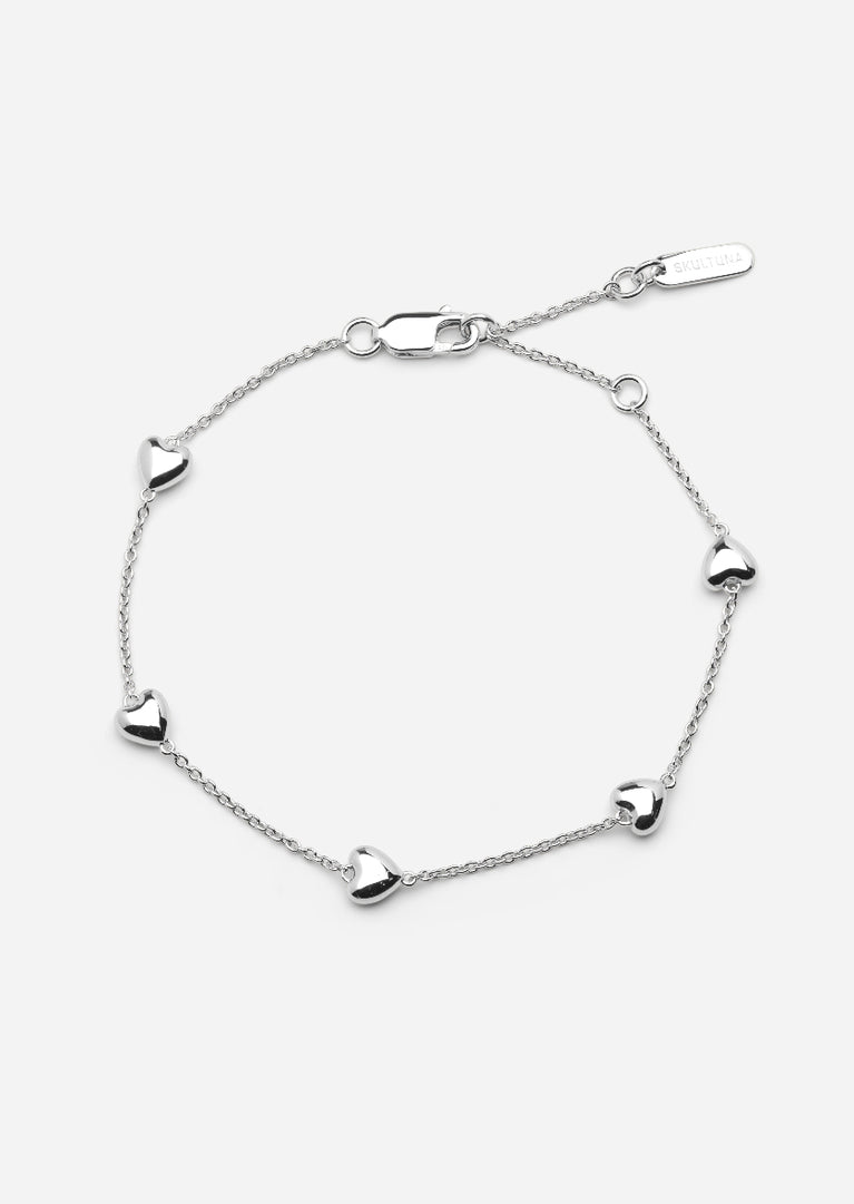 Sterling silver Heart Petit bracelet by Skultuna featuring a delicate heart charm, worn on a wrist with a soft background.
