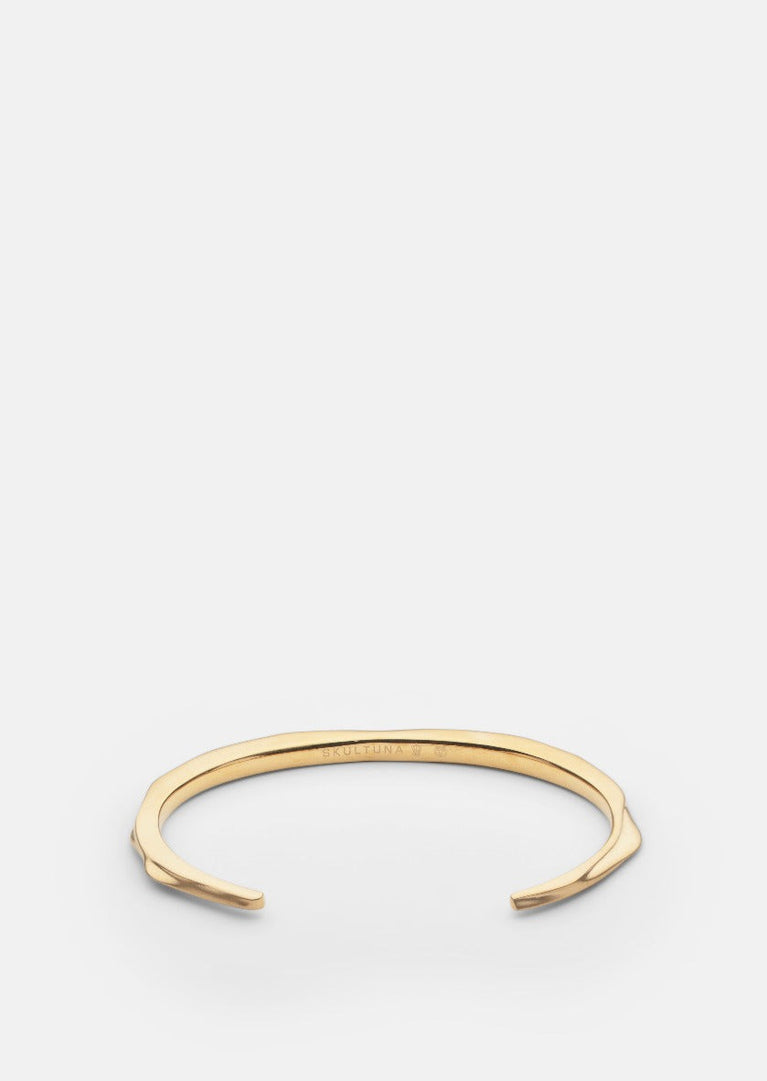 Skultuna matte gold plated Opaque Objects cuff bracelet, shown from a side angle with a sleek, modern design.