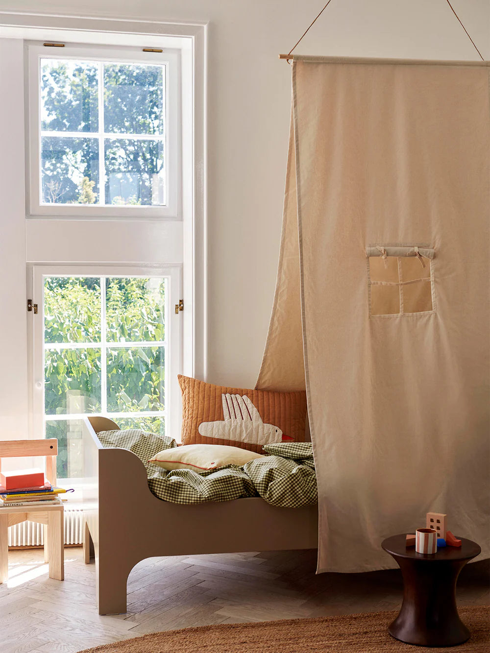 Off-white Ferm Living Kids Settle Bed Canopy hanging above a bed, creating a cozy and stylish space for children.