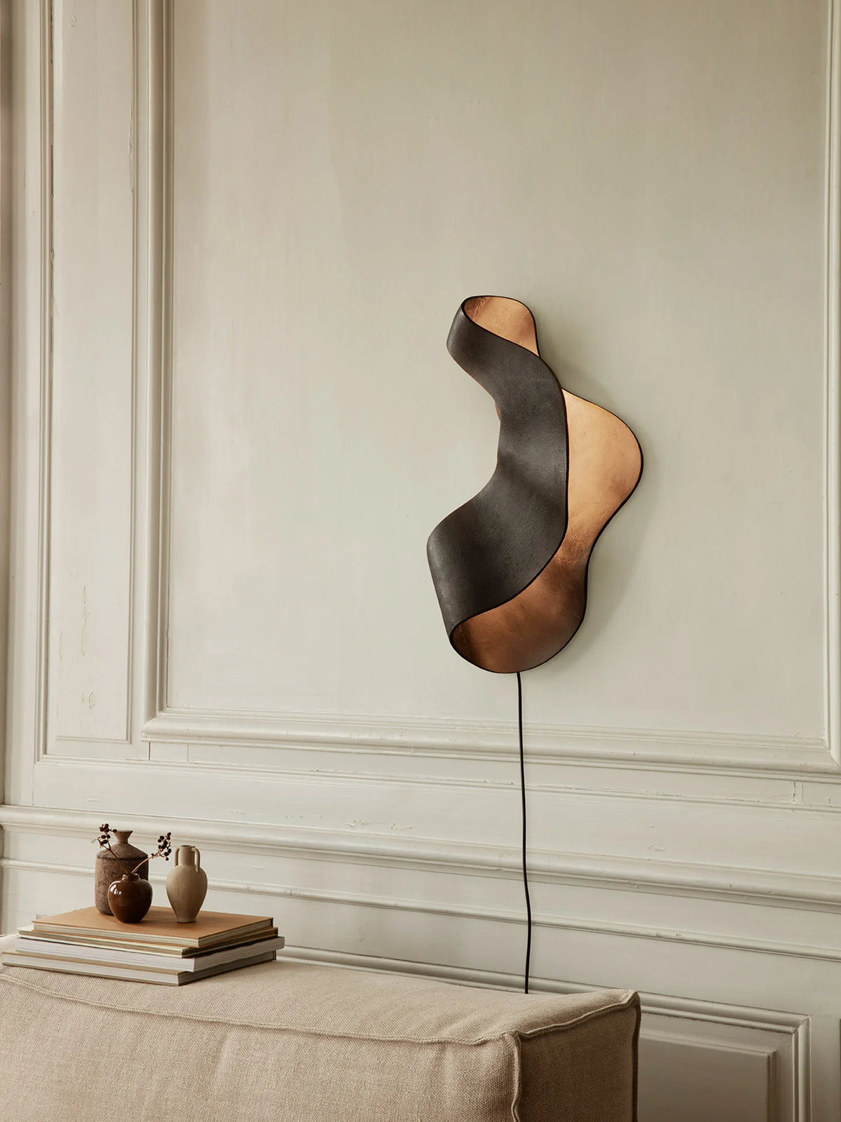 Ferm Living Oyster wall lamp with curved design and soft white shade, mounted on a wall for modern lighting decor.