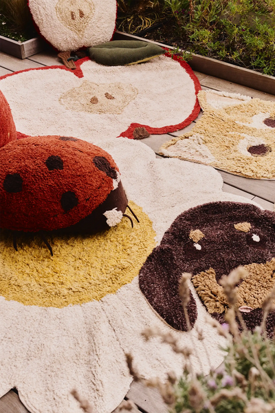 Kids floor cushion featuring Maria the Ladybug by Lorena Canals, soft fabric with red and black ladybug design, ideal for children's rooms.
