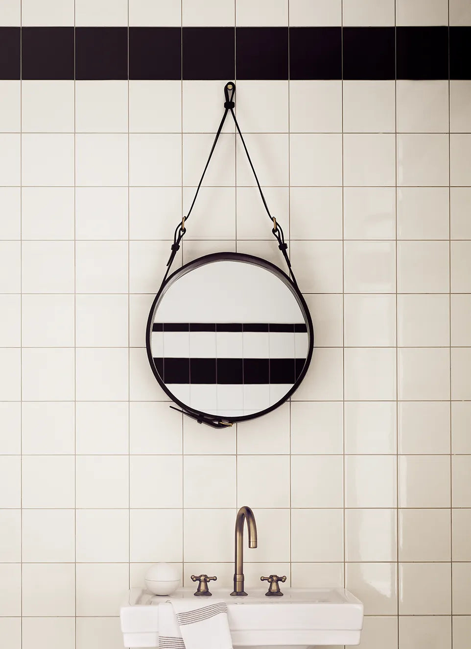 Circular Gubi Adnet Wall Mirror with black leather frame, stylish wall accessory with sleek, modern design.