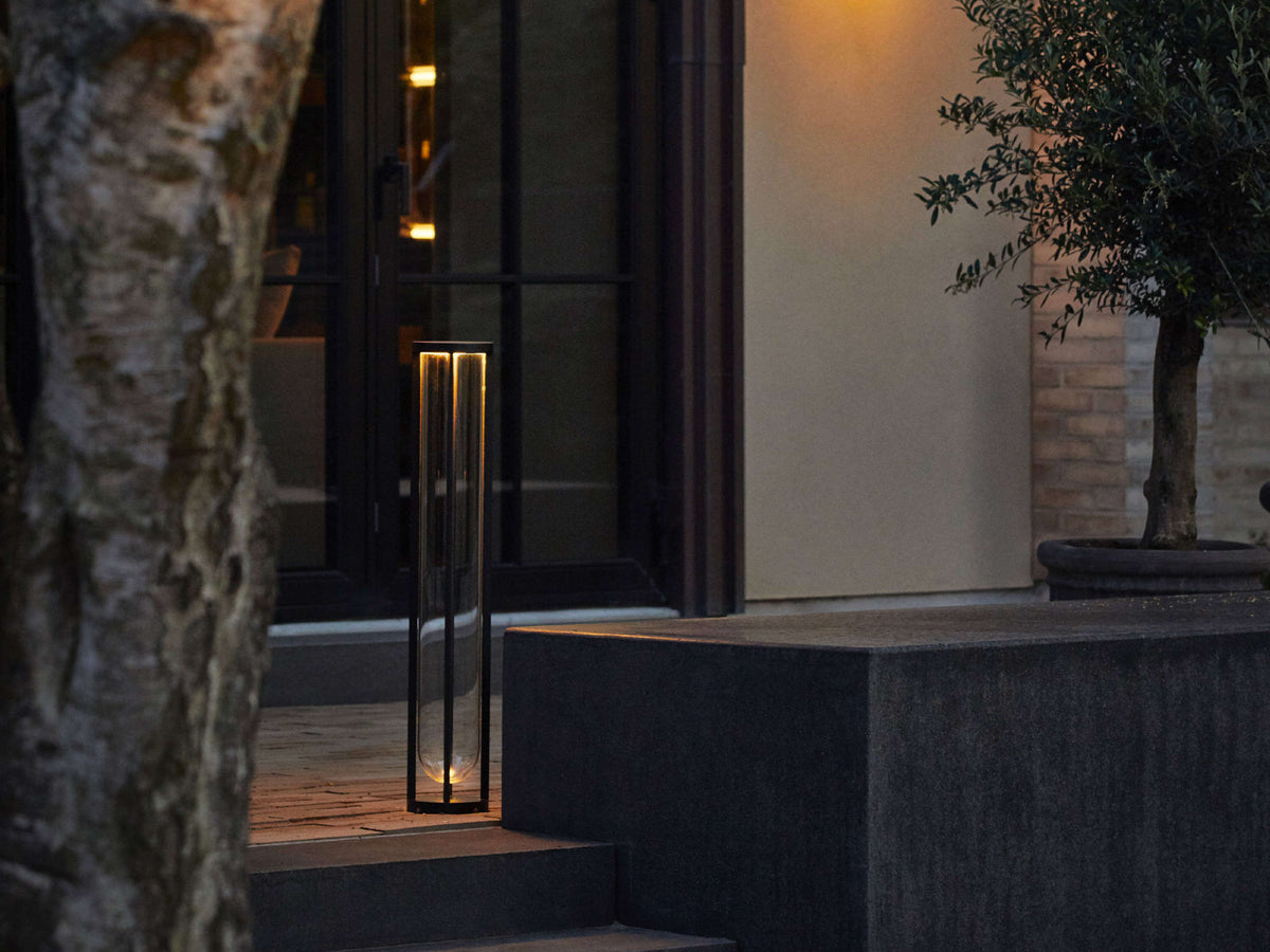 Modern Flos In Vitro Bollard 3 outdoor lighting fixture with sleek design and durable metal finish, illuminated at night.