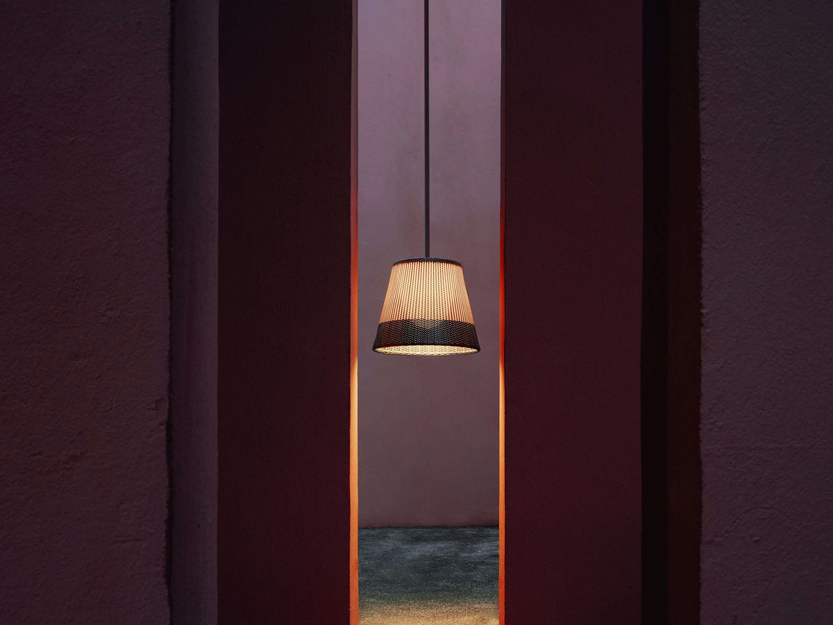 Contemporary Romeo outdoor lighting fixture by Flos with sleek design, installed on a patio with greenery in the background.