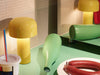 Bellhop Portable Table Lamp by Flos in yellow, shown in a stylish living room setting, highlighting its modern design and compact size.