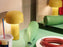 Bellhop Portable Table Lamp by Flos in yellow, shown in a stylish living room setting, highlighting its modern design and compact size.