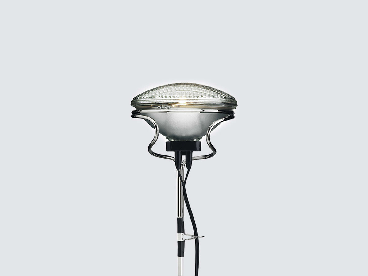 White Toio floor lamp by Flos in modern living room setting, showcasing sleek lighting design and adjustable arm.