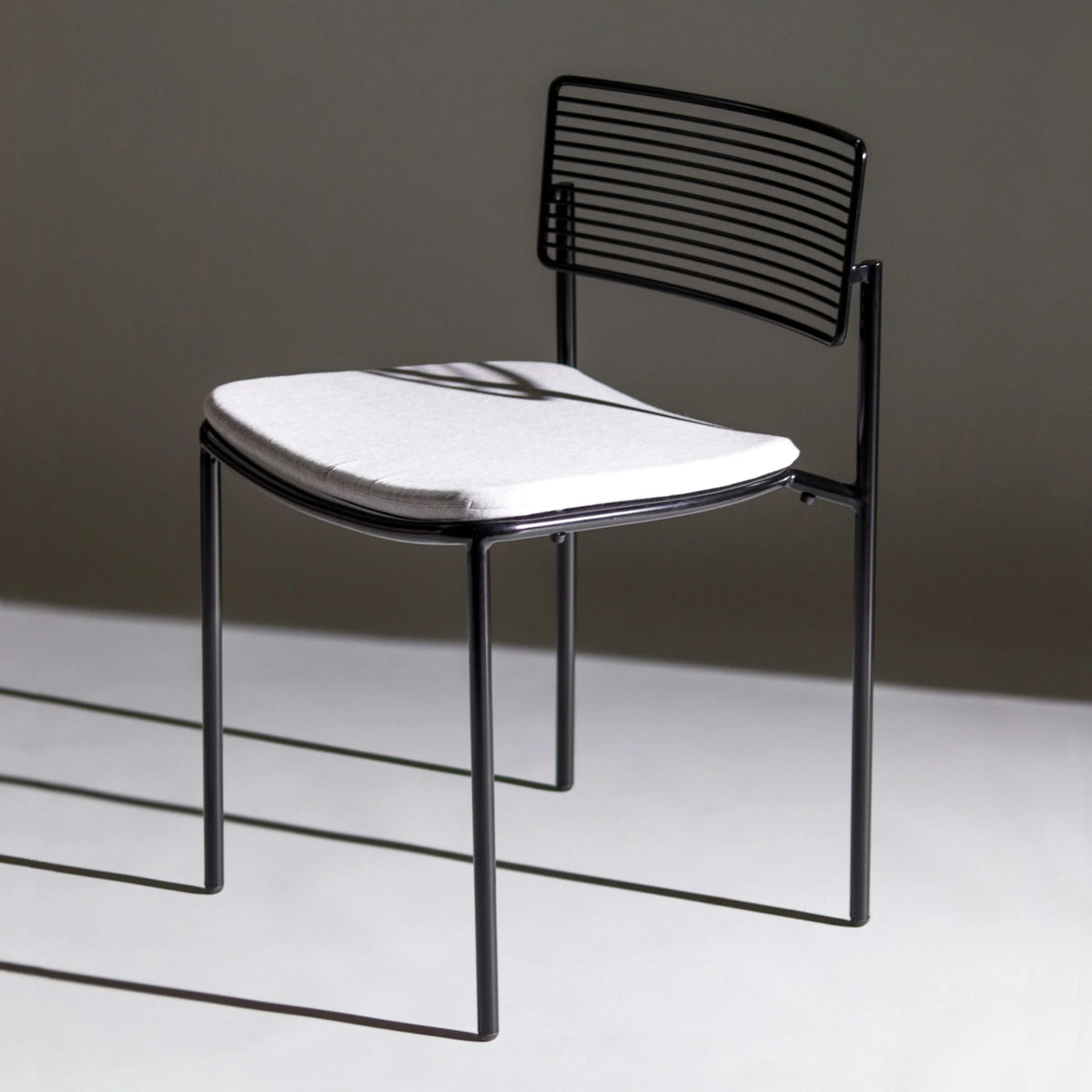 Bend Goods Rachel Chair in black metal with woven seat, modern seating piece with sleek design and curved backrest.