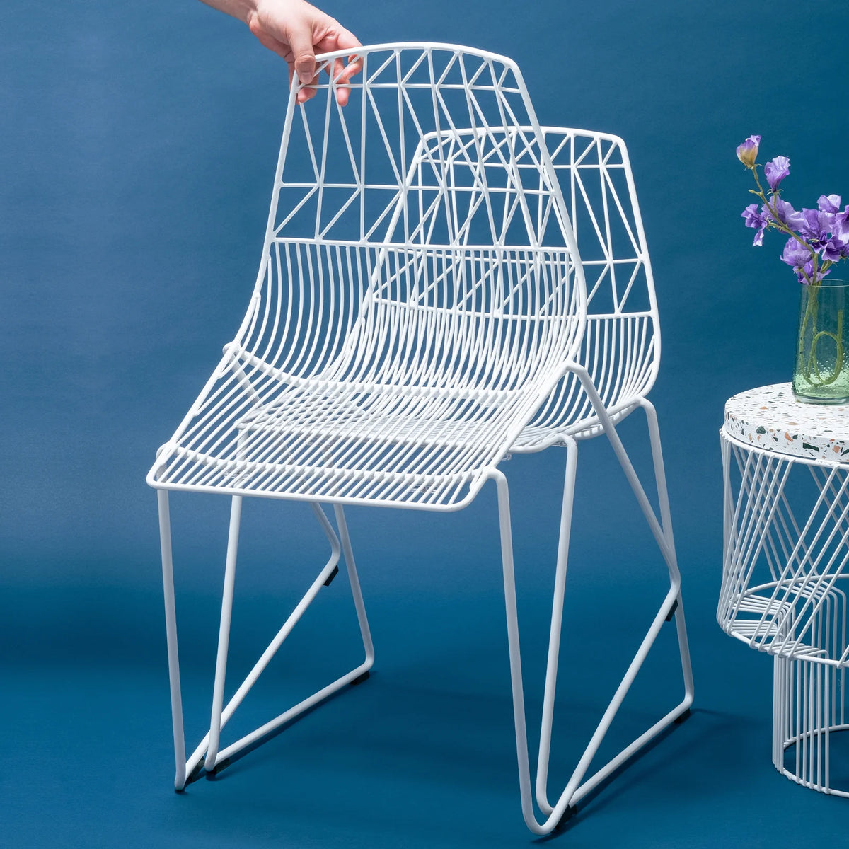 Stacking Lucy seating by Bend Goods, a modern woven chair with a sleek design, shown in white with a black background.