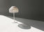 White Tatou table lamp by Flos, modern lighting with sleek design, featuring a curved shape and smooth finish.